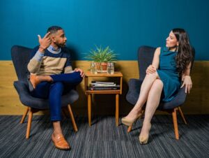 Two professionals in business attire engage in a thoughtful discussion sitting in a stylish, modern room.
