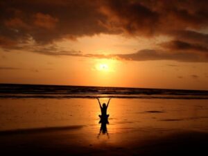 Peaceful meditation silhouette at sunset on a serene beach.